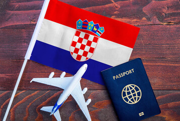 Flag of Croatia with passport and toy airplane on wooden background. Flight travel concept