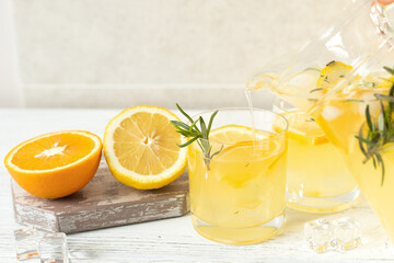 Female hand pours citrus cold lemonade into glasses, summer drinks in hot weather