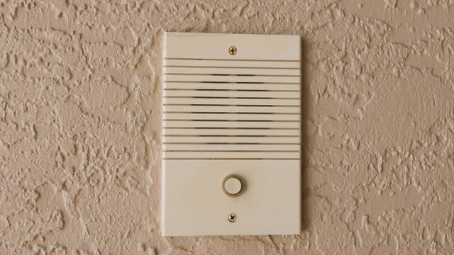 Ringing doorbell with thumb. Closeup of male hand pushing home intercom door bell button.