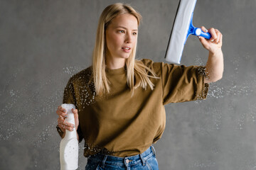 Young european woman cleaning glass with streak and spray