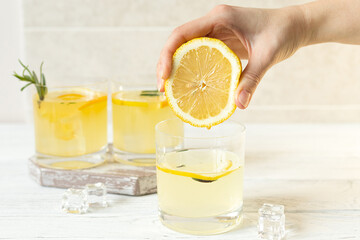 Female hand squeezes lemon into water, summer vitamin drink