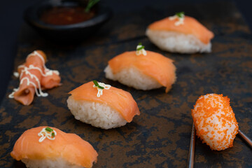 Sushi rolls nigiri with salmon  and salmon eggs in a stone and black background