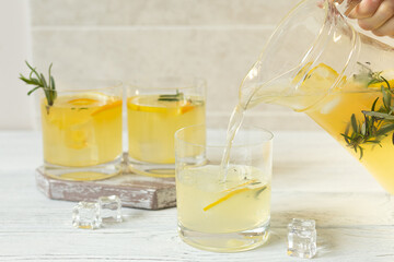 Female hand pours citrus cold lemonade into glasses, summer drinks in hot weather
