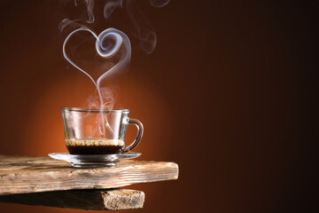 Cup of hot coffee and steam in shape of heart on dark color background