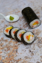 Sushi rolls with salmon avocado tuna and mango in a stone texture background