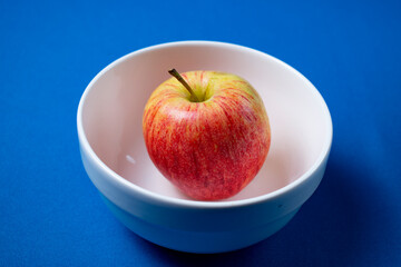 Manzana en bol blanco con fondo celeste