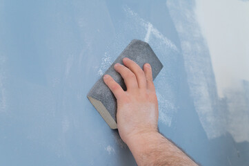 sanding gypsum plaster by hand using sandpaper