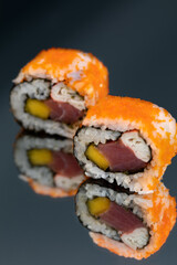 Sushi rolls with salmon avocado tuna and mango in a black background