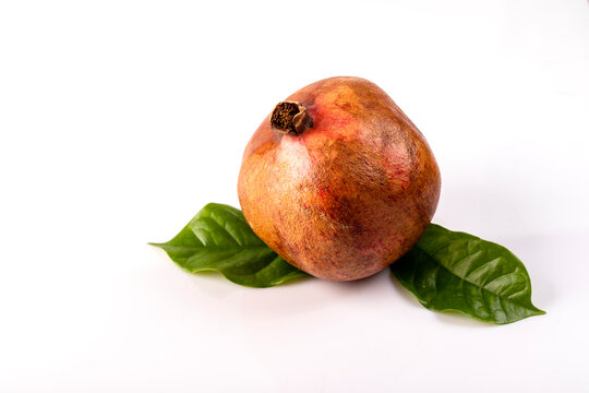 Juicy pomegranate fruit with leaves on the table on a white background.