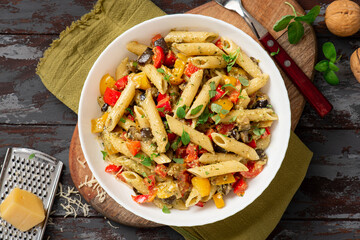 Pasta salad with baked vegetables. Penne pasta with baked peppers, eggplant, pesto and cheese in a...