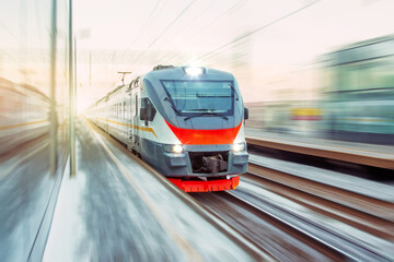 Speed suburban train with motion blur rides city station.
