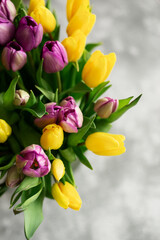 Background: a bouquet of yellow and purple tulips. The concept of spring, holiday, mother's day.