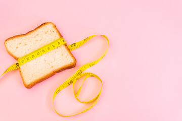 Piece of bread grasped by measuring tape isolated. Diet concept. Copy space for text