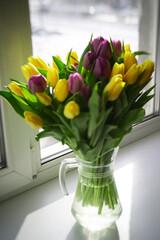 Background: a bouquet of yellow and purple tulips. The concept of spring, holiday, mother's day.