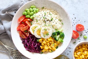 Rice salad with vegetables and sesame on light background. Top view with copy space. Healthy eating.