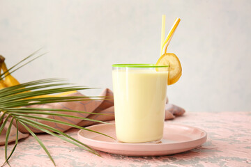 Glass of tasty banana milkshake on color table