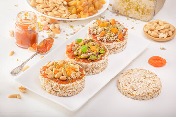 Puffed exploded wheat grains with peanuts and dried apricots, pistachios and sunflower seeds, halva and raisins on a layer of apricot jam on a white plate against a background of oriental sweets.