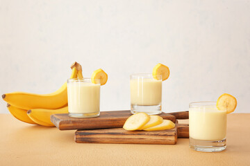 Glasses of tasty banana milkshake on color table