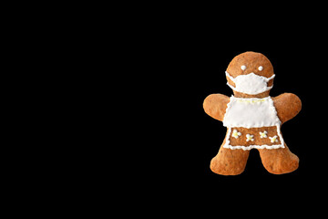 Cute gingerbread woman with protective face mask isolated on black background, copy space for text. Creative concept in coronavirus (COVID-19) time