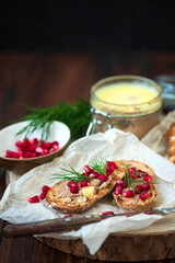 Fresh homemade chicken liver pate on bread with pomegranate seeds and dill over rustic wooden background. Soft focus