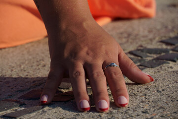 female hand with symbolizing affection resting on the floor. Woman wears orange skirt.