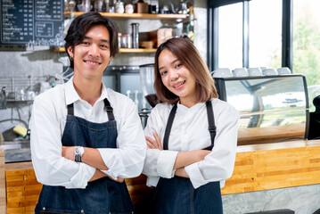 Two Asian barista or coffee maker man and woman stand with arm-crossed or confidence action also...