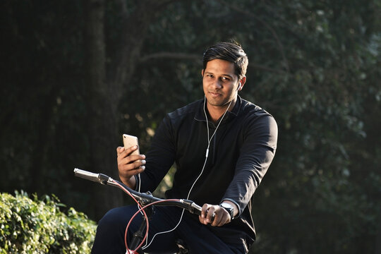 Indian Man Cycling At Park And Listening To Music 