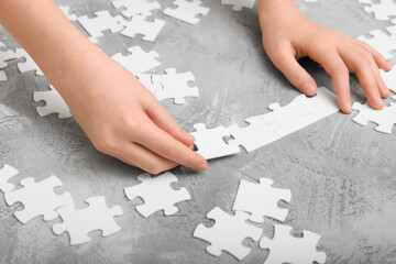 Baby hands assemble the puzzle on the table