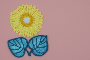  A handmade yellow flower and teal leaves on a pink textile for a positive mood. 