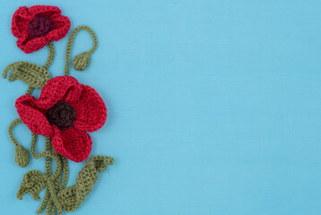 Handmade poppy flowers on the blue textile background.