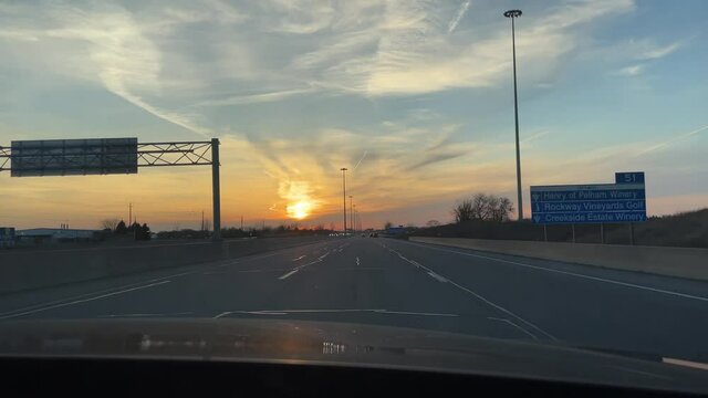 Driving on empty clear highway during sunset afternoon after work evening in Ontario Southern Canada in black sedan