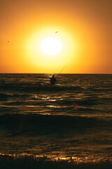 Fisherman catches fish in the sea at sunrise or sunset