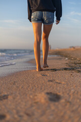 Naklejka premium traces of female steps in the sand. girl walks in short shorts on the beach