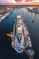 Ship repair and maintenance docks in beautiful sunset colors. Giant cargo vessel being repaired at...
