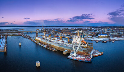 Ship repair and maintenance docks in beautiful sunset colors. Giant cargo vessel being repaired at dockyard in Riga. 