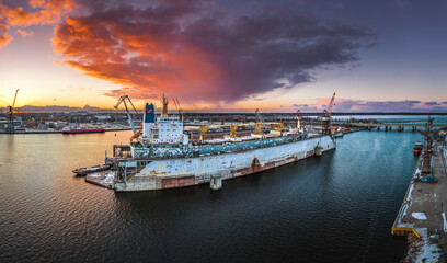 Ship repair and maintenance docks in beautiful sunset colors. Giant cargo vessel being repaired at...