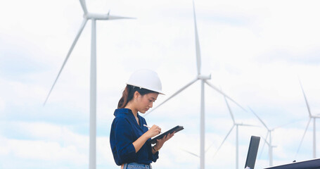 Women engineer using tablet for working on site at wind turbine farm