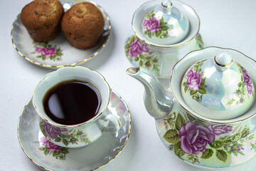 A cup of tea on a white tablecloth. Tea with muffins. Light breakfast. White tea set with flowers.