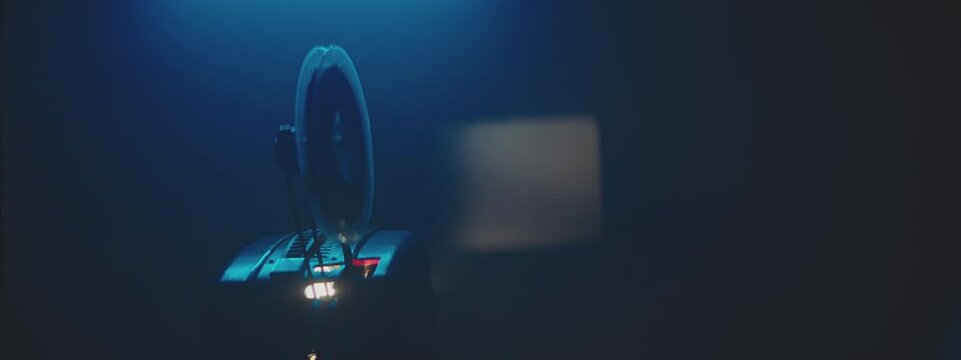 A close-up shot of the film reel of a projector. In the background we see a film projection frame.