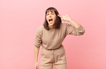 pretty woman looking unhappy and stressed, suicide gesture making gun sign with hand, pointing to...