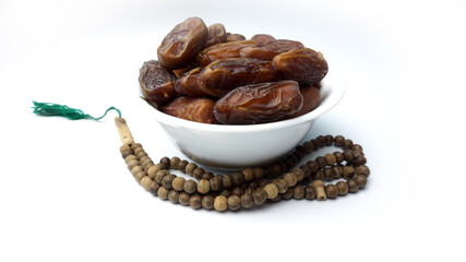 A close up photo of dates and tasbih or rosary beads in white background. Ramadan conceptual photo. Fasting conceptual photo. Copy space.