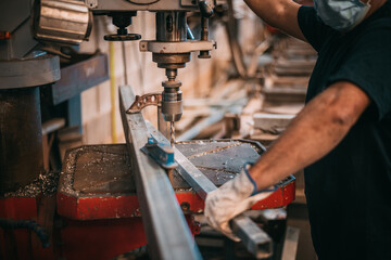 a man works with an industrial machine drilling a piece of metal