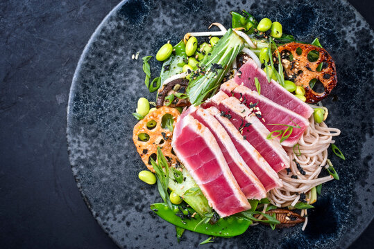 Modern Style Traditional Japanese Gourmet Seared Tuna Fish Steak Tataki With Soba Noodles And Stir-fried Vegetables Served As Top View On A Nordic Design Plate With Copy Space Left