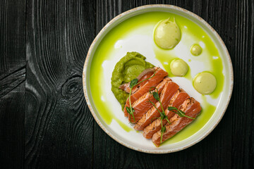 Sauteed salmon with basil sauce on a white round plate
