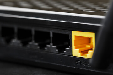 Wireless modem router with yellow cable and LAN port for connection on a black background.