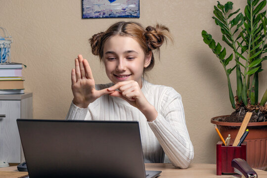 Teenage Girl Deaf Disabled Child School Girl Learning Online Class On Laptop Communicating With Teacher By Video Conference Call Using Sign Language Showing Hand Gesture During Virtual Lesson.