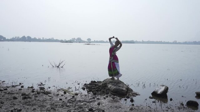 A bharatnatyam dancer displaying a classical bharatnatyam pose in the nature of  Vadatalav lake, Pavagadh. Beautiful indian girl dancer in the posture of Indian classical dance bharatanatyam .