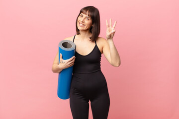 athlete woman smiling and looking friendly, showing number three or third with hand forward,...