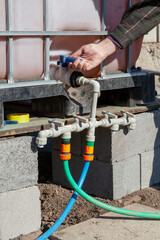 Hand opens tap on plastic irrigation system