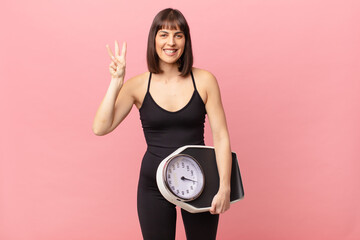 athlete woman smiling and looking friendly, showing number three or third with hand forward,...